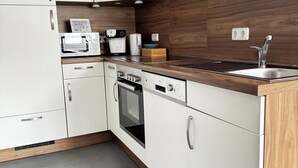 Eine moderne Küche mit weißen Schränken, einem Einbauofen, einer Mikrowelle und einer Kaffeemaschine.