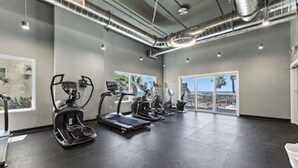 A gym with treadmills, ellipticals, and stationary bikes arranged in a row. - Cozy beach condo with many amenities for fun and relaxation conveniently located (Orange Beach)