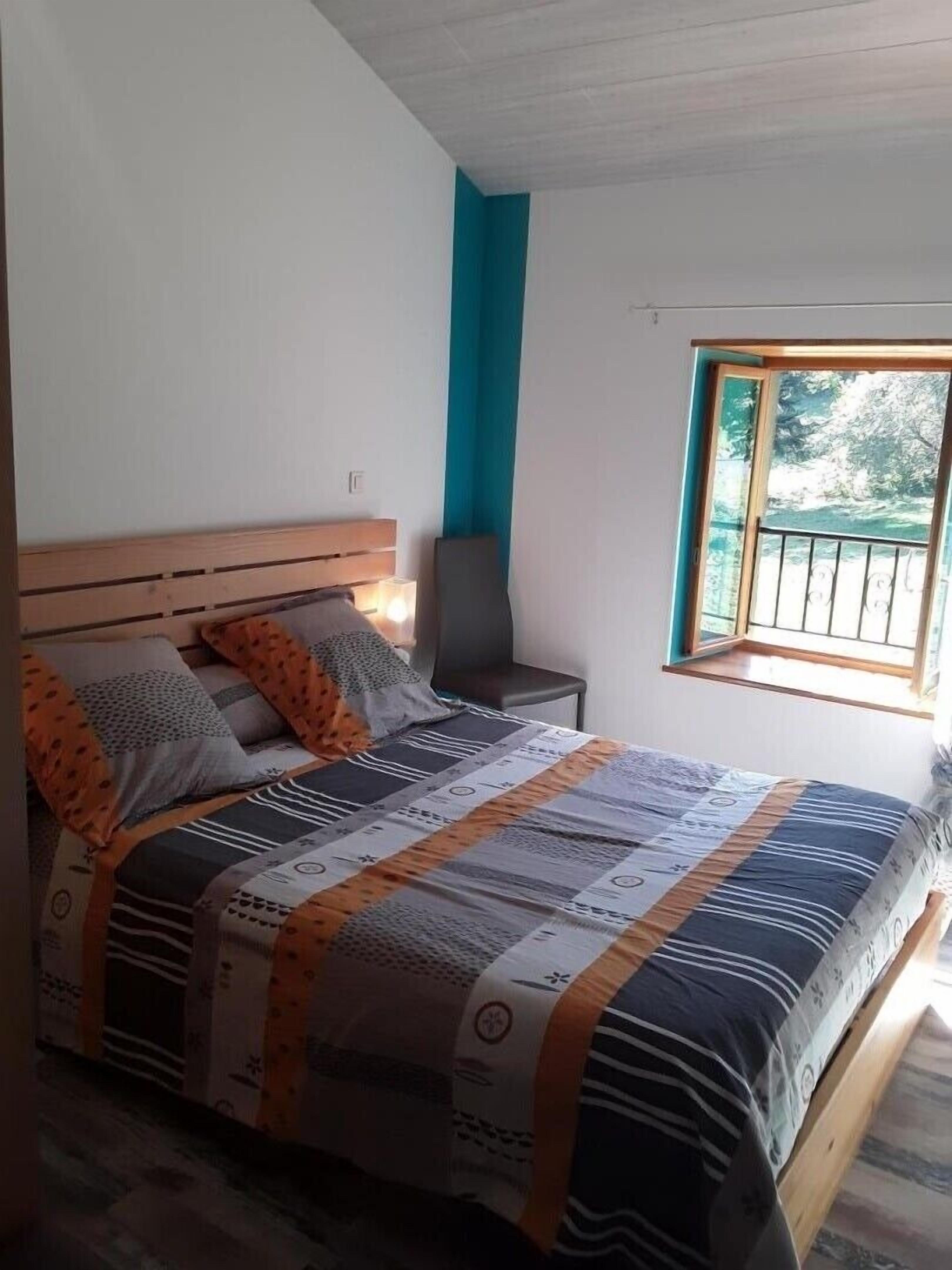 Une chambre à coucher avec un lit, une table de chevet, une chaise et une fenêtre donnant sur un beau paysage.