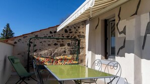 A small outdoor seating area with a table and chairs, a green chair, and a patterned cushion. - Gite DU Vigneron - Orbeil (ORBEIL)