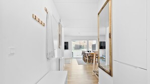 A modern, minimalist hallway with white walls, a wooden floor, and a dining area with a large mirror and table. - Awesome home in Nivå with WiFi (Nivå)