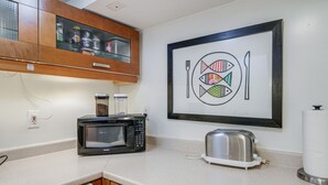 Cozinha com micro-ondas, torradeira e uma obra de arte emoldurada na parede.