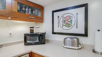 Une cuisine équipée d’un four à micro-ondes, d’un grille-pain et ornée d’œuvres d’art encadrées au mur.