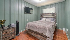 A bedroom with a bed, a dresser, a TV mounted on the wall, and a radiator. - Atlanta's East Point charm, just a 13-min drive away from Mercedes-Benz Stadium (East Point)
