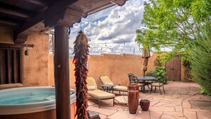 Un patio con sillones de descanso, un jacuzzi y suelo de piedra.