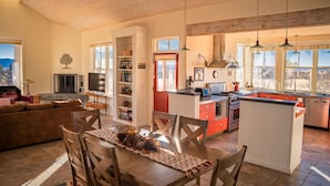 Une cuisine spacieuse avec un îlot central, un coin repas avec une table dressée, et un salon avec un canapé.