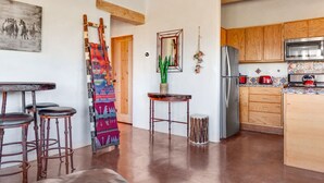 A kitchen with wooden cabinets, a stainless steel refrigerator, and a tiled backsplash. - Casita de Alfarero -  A Peaceful Escape - New Hot Tub! (El Prado)