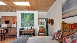 Un dormitorio acogedor con una cama grande, cabecera de madera y vista al área de la cocina.