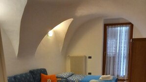A cozy room with a sofa, a small table, and a bed with a blue bedspread.