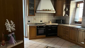 A kitchen with wooden cabinets, a gas stove, a microwave, and a tiled floor with a decorative rug.