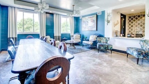 Une salle de conférence spacieuse, dotée d’une longue table et de chaises, d’un coin salon avec des canapés et des fauteuils, et d’une grande fenêtre agrémentée de rideaux.