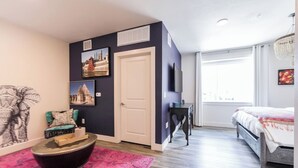 A modern bedroom with a bed, a TV, a door, and a window. - Comfort Studios, 1 Queen(Mumbai) (Dallas)