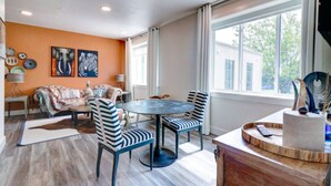 Un salon moderne avec une table ronde, des chaises à rayures, un canapé et des œuvres d’art accrochées aux murs.