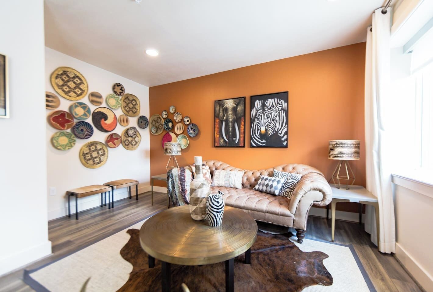 A living room with a tufted sofa, a round coffee table, and a wall adorned with various decorative plates.