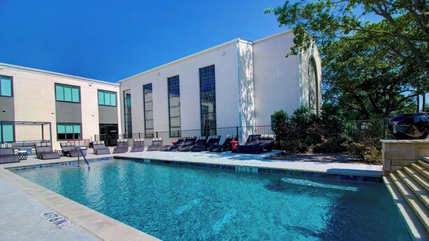 A swimming pool with lounge chairs and a building with large windows. - Comfort Studio,1 King Bed 207 (Dallas)