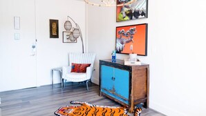 A room with a white door, a striped chair, a blue cabinet, and a tiger rug. - Rare Studio,1 Queen Bed(Beijing) (Dallas)