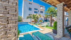 Una piscina con lettini, un muro in pietra e un edificio sullo sfondo.
