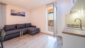 Un soggiorno moderno con un divano angolare grigio, un tavolino in vetro e vista su un balcone con ringhiera.
