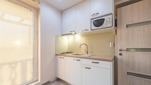 Una cucina compatta con forno a microonde integrato, lavello e piano cottura a gas.