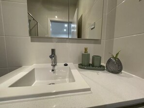 A bathroom with a white sink, a mirror, and a toilet. - Cosy Sunlit Home Away from Home

 (Baulkham Hills)