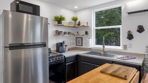 Una cocina moderna con electrodomésticos de acero inoxidable, encimeras de madera y estantes empotrados con plantas.