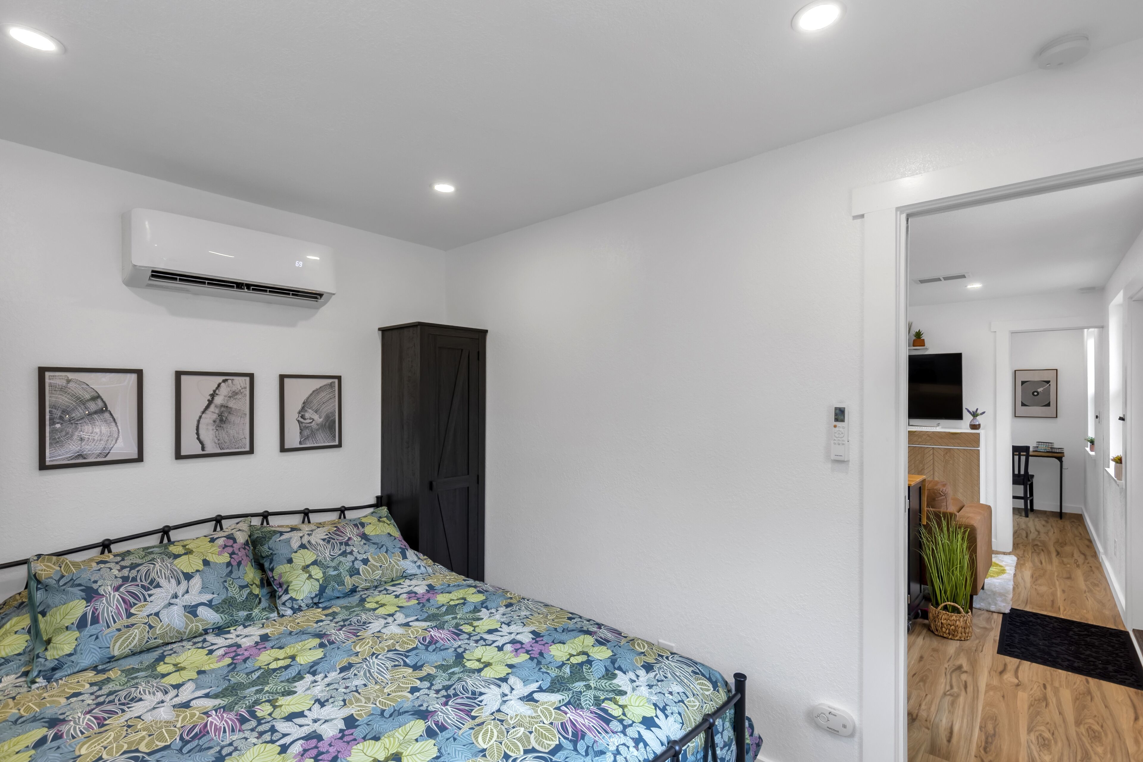 Een slaapkamer met een bloemenbedekking, een donkere garderobe en een wandairconditioner.