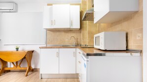 A modern kitchen with white cabinets, a wooden table, a microwave, and a sink. - WintowinRentals Comfortable apartment in Málaga (Málaga)