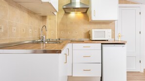 A modern kitchen with white cabinets, a stainless steel sink, a microwave, and a built-in oven. - WintowinRentals Comfortable apartment in Málaga (Málaga)