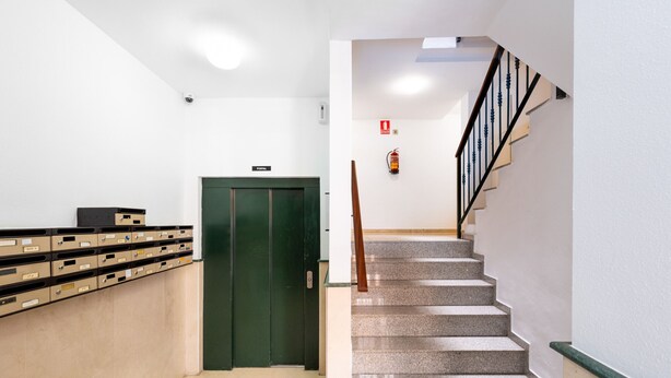 A clean, modern lobby with a green elevator, a staircase with a wooden handrail, and a row of beige filing cabinets. - WintowinRentals Comfortable apartment in Málaga (Málaga)