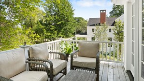 Eine überdachte Veranda mit Korbmöbeln und Blick auf benachbarte Häuser.