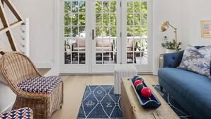 Ein Wohnzimmer mit einem Korbstuhl, einem blauen Sofa und einem Couchtisch mit Dekoration.