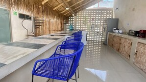 A long bar area with blue chairs, a thatched ceiling, and a kitchen counter with appliances. - Cancun hotel downtown, private bedrooms with private bathroom, shared pool (Cancún)