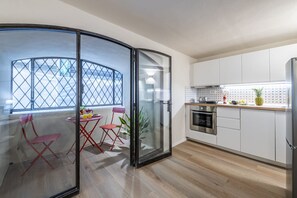 A modern kitchen with white cabinets, a stainless steel oven, and a glass partition.
