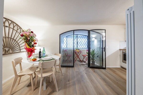 A dining area with a round table, chairs, a vase of flowers, and a glass partition.