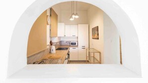 Una cocina pequeña con armarios blancos, un microondas y una lámpara colgante.