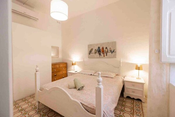 A bedroom with a bed, two bedside tables, a dresser, and a wall-mounted artwork of birds. - Harbour view 2 bedroom apartment overlooking harbour (Senglea)