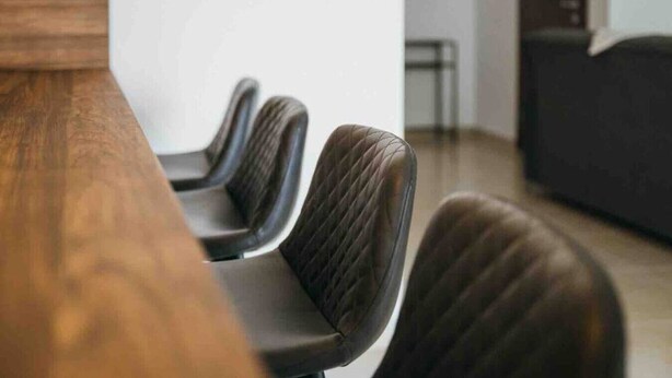 Een vergaderruimte met een lange tafel en vier stoelen.
