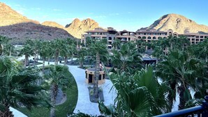 Un complexe hôtelier doté d’une piscine, de palmiers et avec des montagnes en toile de fond.