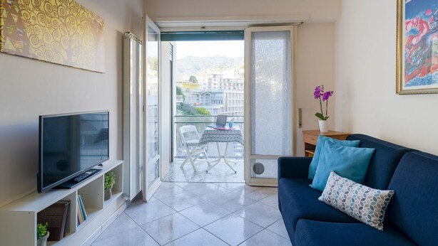 Ein Wohnzimmer mit Fernseher, Sofa und Balkon mit Tisch und Stühlen.