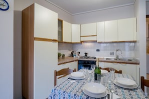 Una cocina compacta con armarios blancos, estufa a gas y pileta.