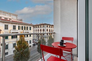 A balcony with a red table and chairs, overlooking a street with buildings and a tree. - GuestHost - Modern and bright 40 sqm apartment, located on the second floor of a modern building (with lift), for 4 people. The accommodation is located in a residential district, equipped with all the main services and well connected to the historic cen (Firenze)