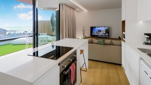 A modern kitchen with a large window, a dining area with a view, and a living room with a TV. - Paraisos de Agaete Penthouse Views (El Turman)