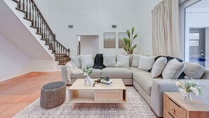 A modern living room with a staircase, a sofa set, a coffee table, and a view of the outdoors. - Valrico Villa: Pool, Spa, Court & Game Room (Valrico)