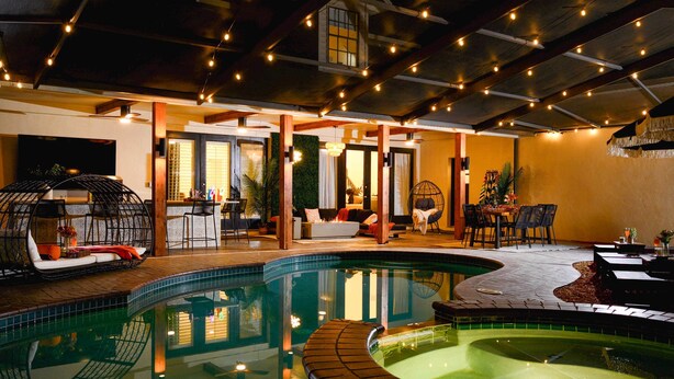 An indoor swimming pool with a curved design, surrounded by seating areas and a bar. - Valrico Villa: Pool, Spa, Court & Game Room (Valrico)