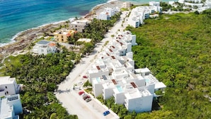 An aerial view of a coastal resort with white buildings, a beach, and lush greenery. - Oceanfront Seahorse | Private Hot Tub Beach Access (Akumal)
