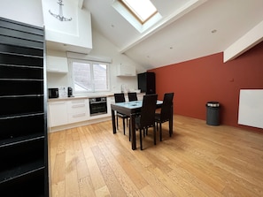 A modern kitchen with white cabinets, a black countertop, and a dining area with a table and chairs.