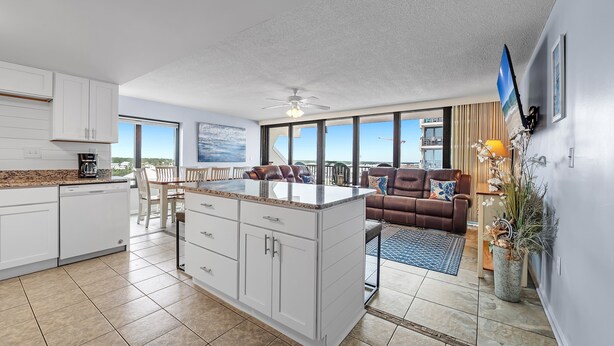 Een moderne keuken met witte kastjes, een centraal eiland en een eethoek met tafel en stoelen.