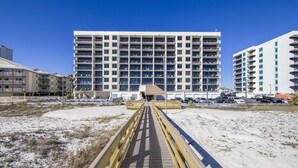 Een meerlaags hotel met balkons, een ligging aan het strand en een voetgangersbrug naar de ingang.