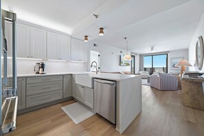 A modern kitchen with white cabinets, a dishwasher, and a coffee machine.