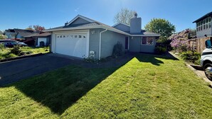 A single-story house with a garage, a well-maintained lawn, and a clear blue sky.
